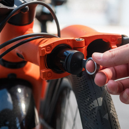 Person removing Brompton Toolkit from a Brompton G Line on an orange and black bike with a blurred background