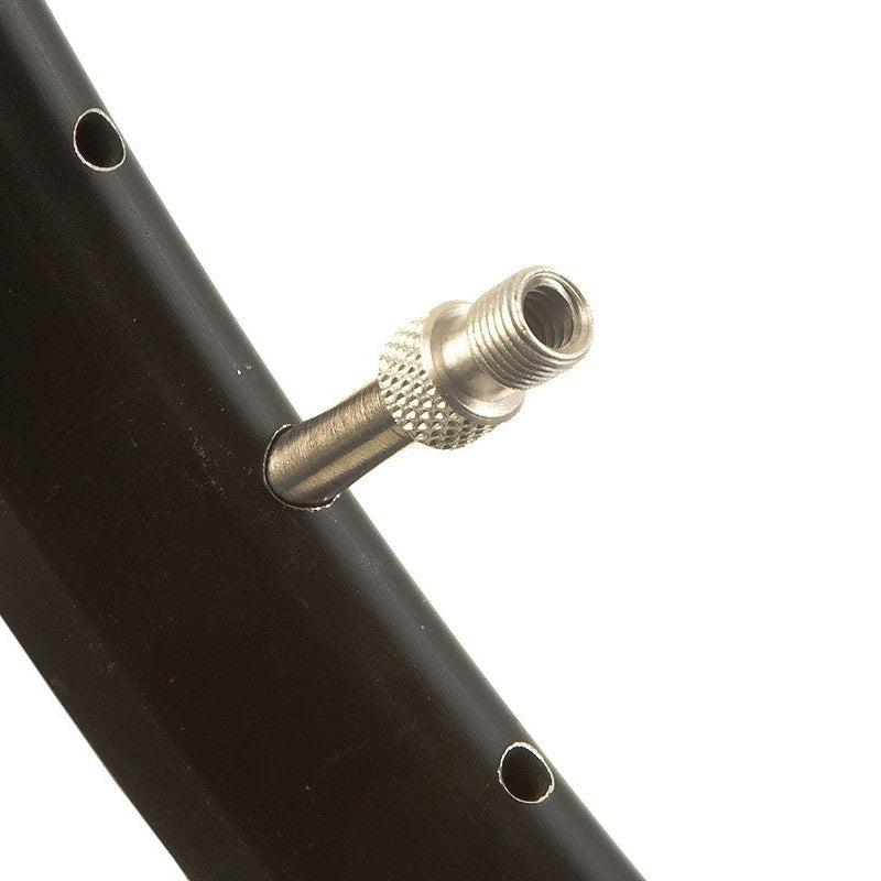 Close-up of a black bicycle rim with a gold valve stem on a white background