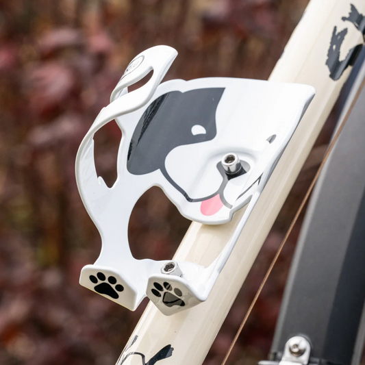 Dog-shaped bottle holder attached to a bicycle frame with a blurred natural background