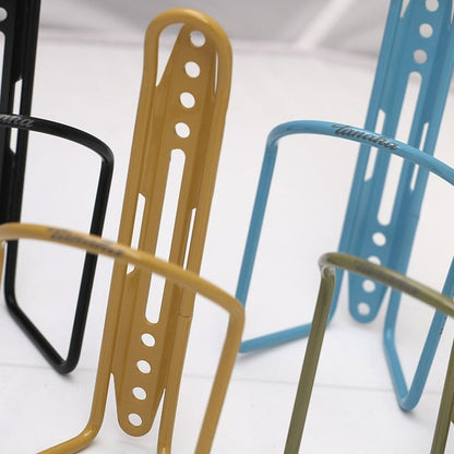 Metal bottle cages in gold, blue, and black on a white background