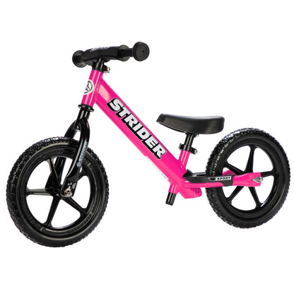 Pink Strider balance bike on a white background