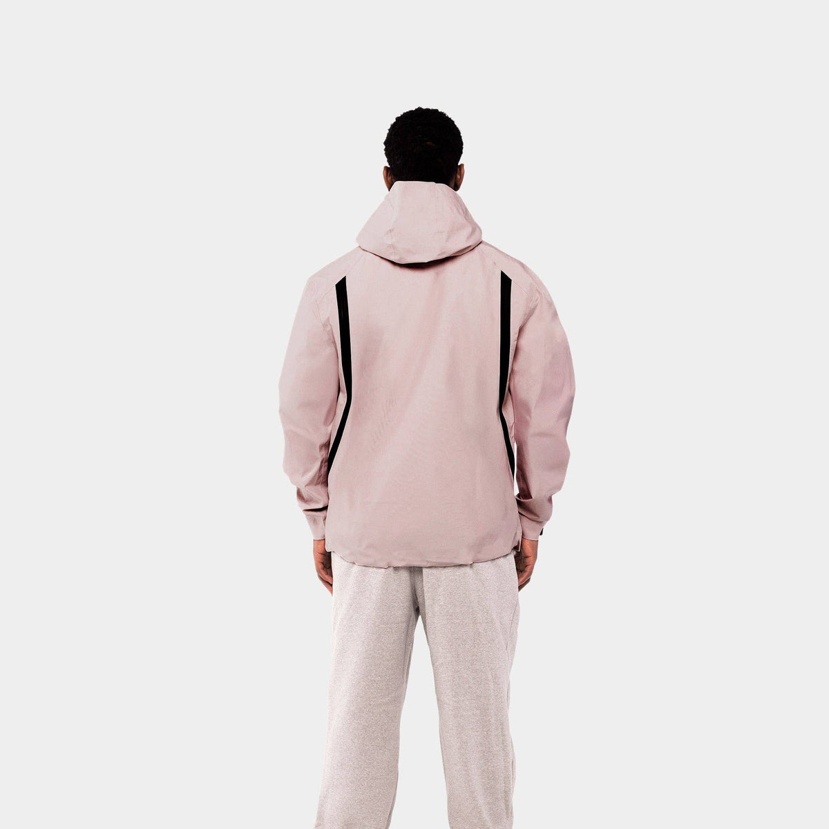 Person wearing a light pink jacket and beige pants on a white background