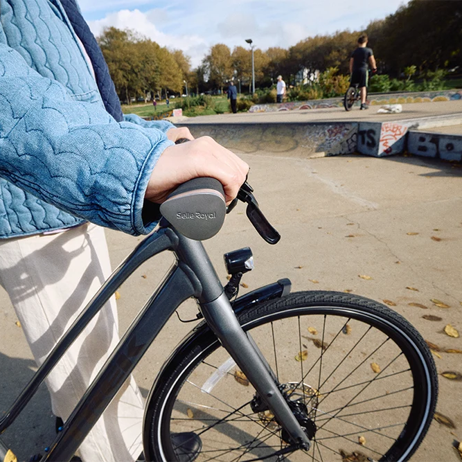 Person holding a bicycle handlebar with a park in the background
