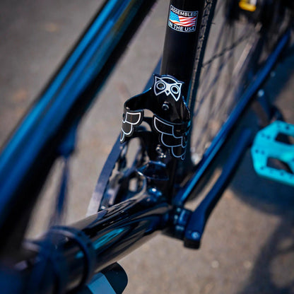 Close-up of a bicycle frame with a visible brand logo on a blurred road background