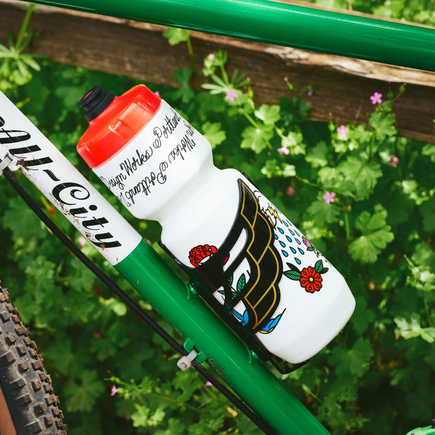Bicycle water bottle with decorative design on a green bike frame against a blurred natural background