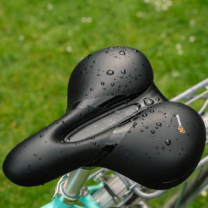 Black bicycle seat with water droplets on a blurred green background