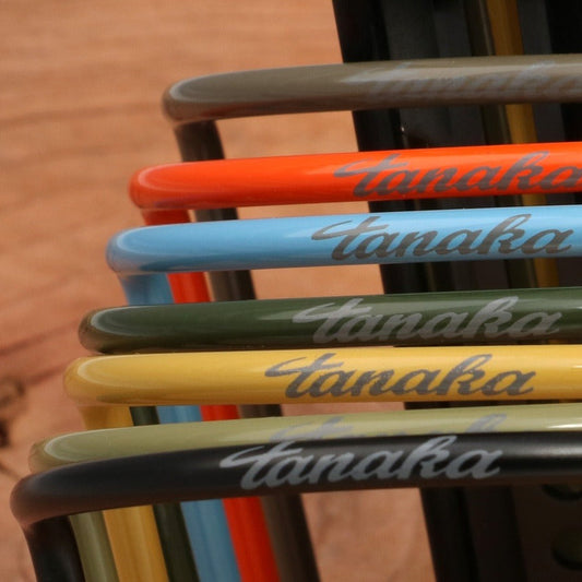Set of colorful paintbrush handles with 'Tanaka' branding on a blurred background