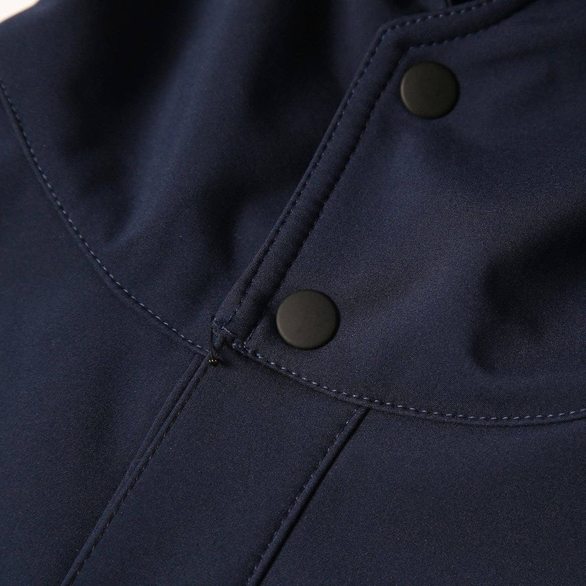 Close-up of a navy blue garment with dark snap buttons and visible stitching details.