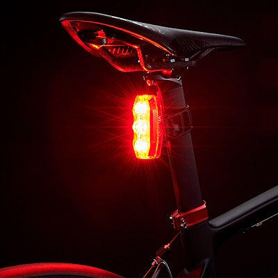 Bicycle tail light attached to a bike seat on a dark background