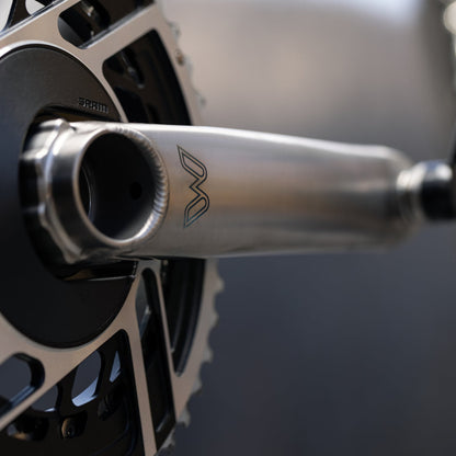 Close-up of a bicycle crankset with a brand logo on a blurred background