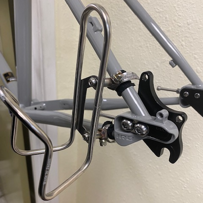 Bicycle water bottle holder attached to a bicycle frame against a neutral background