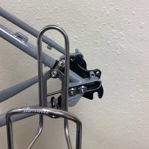 Close-up of a bicycle frame with water bottle holder against a light gray wall.