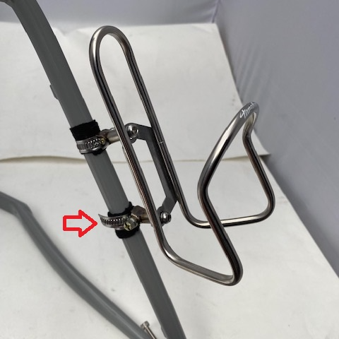 Metal bike water bottle holder attached to a bicycle frame with a red arrow pointing to a small component.