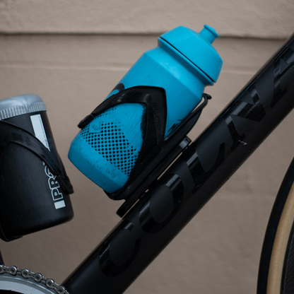 Blue bicycle water bottle holder attached to a bike frame with a blurred background