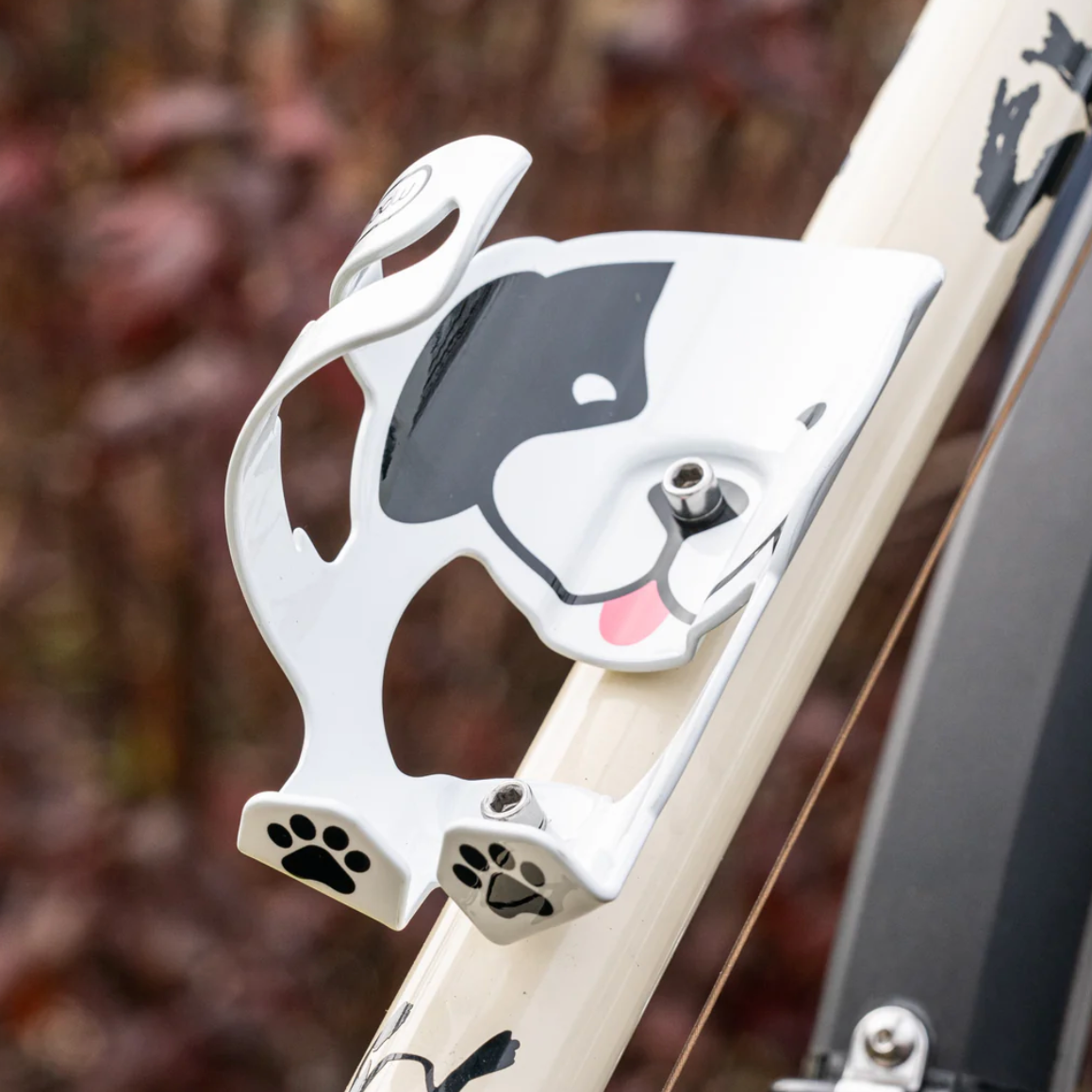 Dog-shaped bottle holder attached to a bicycle frame with a blurred natural background